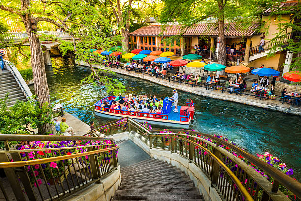 San Antonio, Texas, USA - April 14, 2013: Tourists riding in tour boat and eating at restaurants along The Riverwalk in San Antonio Texas. The San Antonio Riverwalk is a world-famous park and walkway along the scenic canal of the San Antonio River, in downtown San Antonio Texas.